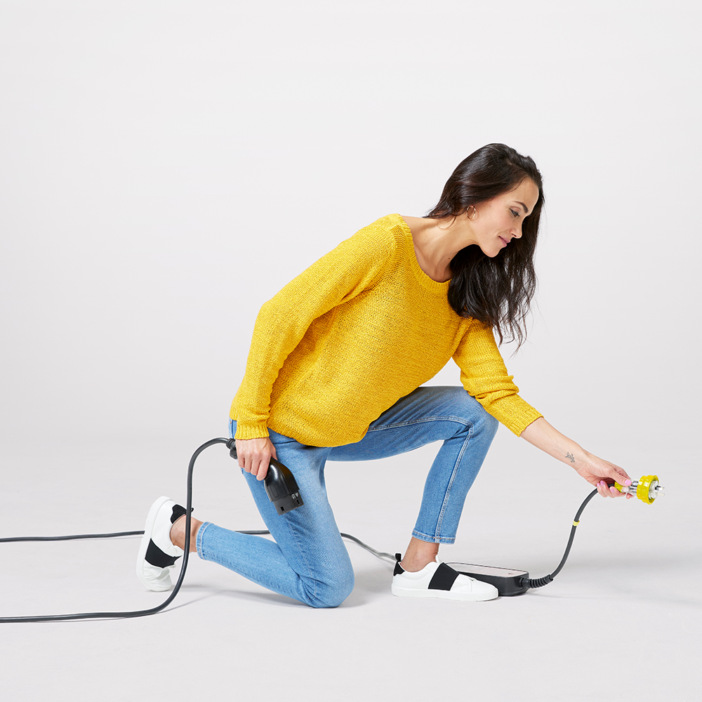 Women in yellow sweater plugging a power cord in.