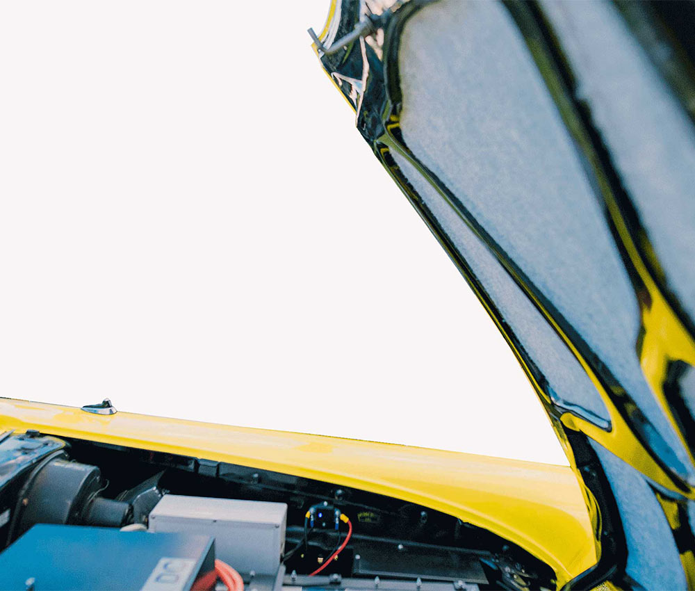 A raised hood of a Ford Fairline, showing batteries below.
