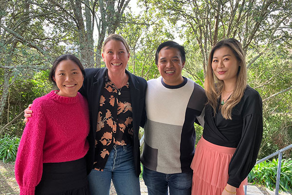 A smiling group of people in front of greenery.