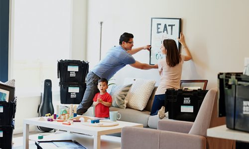 Mother and Father hanging a picture in their new home with their son