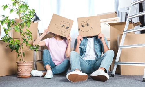 two people moving house in winter surrounded by household items with cardboard boxes on their head