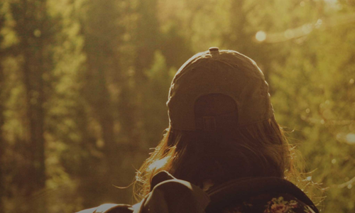 Back of a woman with a cap in the woods