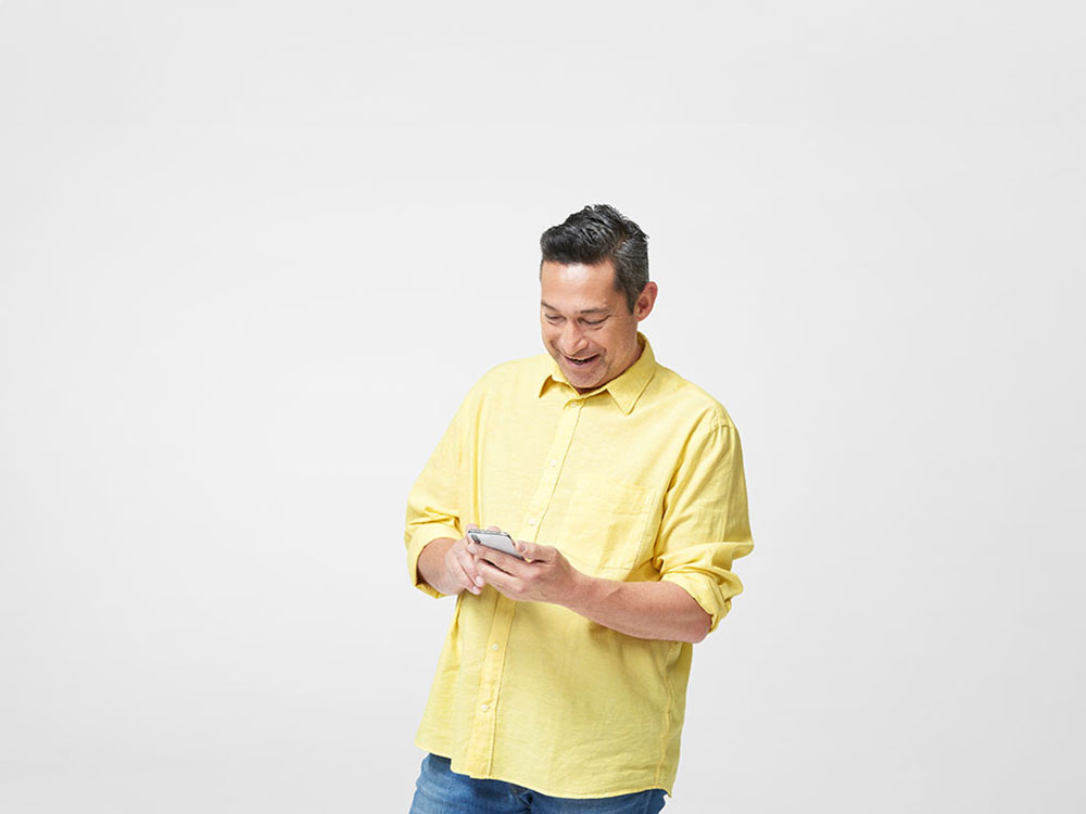 Man in yellow shirt checking his phone.