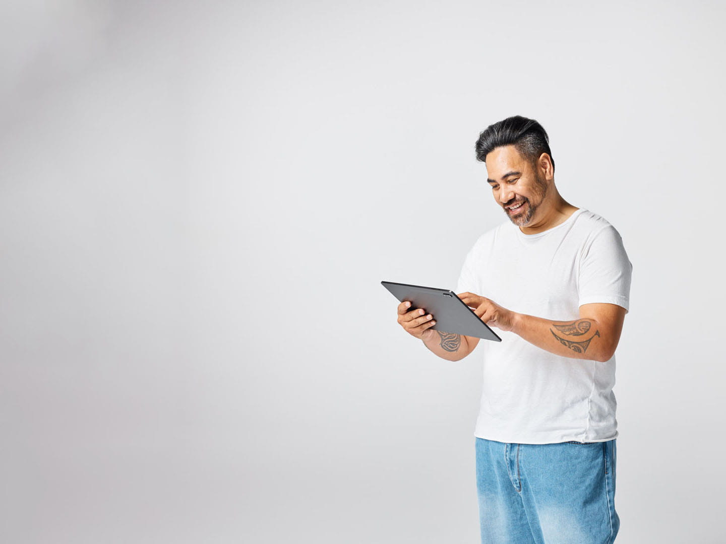 A man in a white t-shirt browsing on his tablet