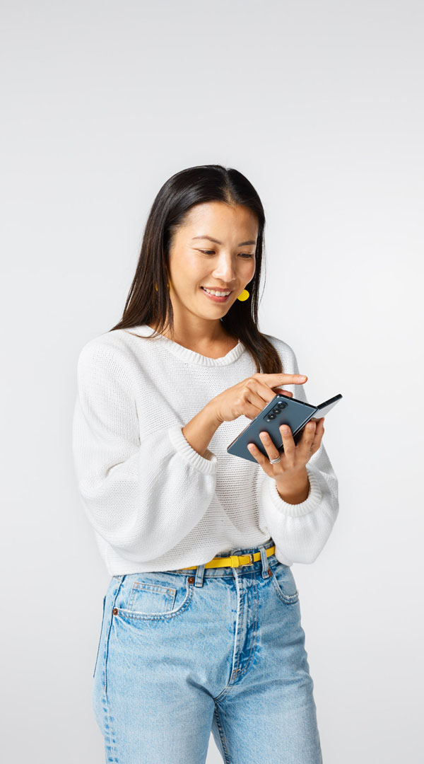 Woman in blue jeans and a white top is browsing the internet on her mobile phone